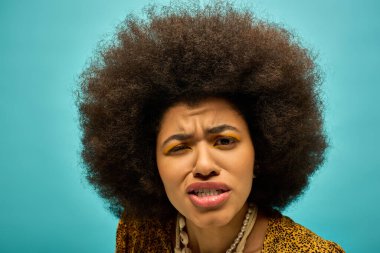 Kıvırcık saçlı, modaya uygun giyinmiş şık bir Afrikalı Amerikalı kadın, şaşırmış görünüyor..