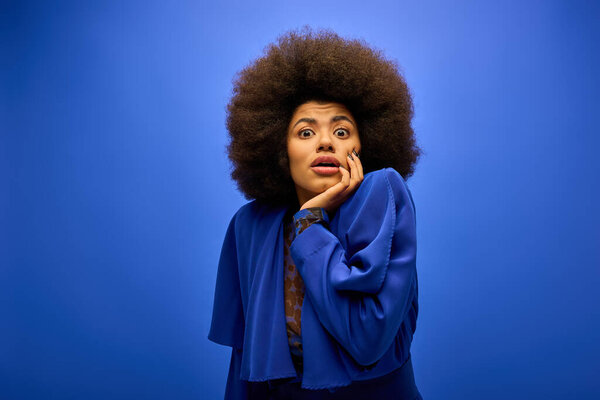 A stylish African American woman with curly hairdoposing in trendy attire against a vibrant backdrop.