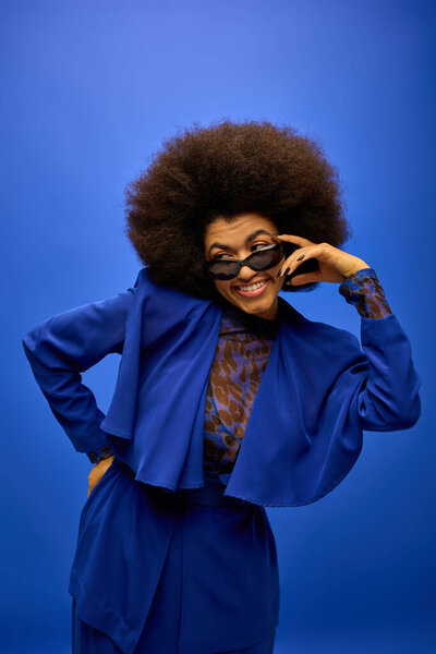 Trendy African American woman with curly hairdo against colorful backdrop.