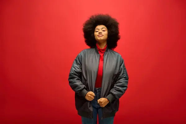 African American Woman Curly Hairdostands Confidently Front Vibrant Red Background — Φωτογραφία Αρχείου