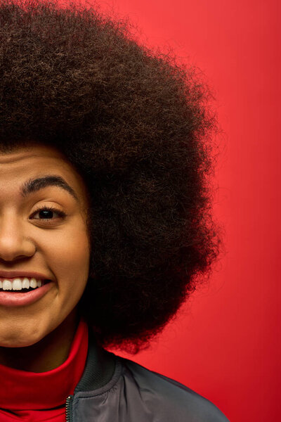 Trendy African American woman with curly hairdosmiling joyfully.