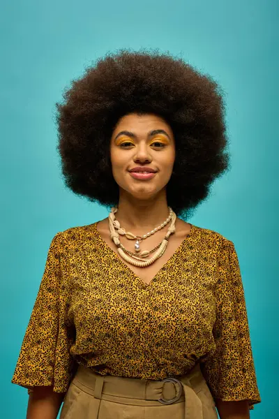 stock image Trendy African American woman in afro hairstyle poses stylishly against a vivid blue backdrop.