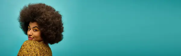 stock image Trendy African American woman poses with curly hairdoon vibrant blue backdrop.