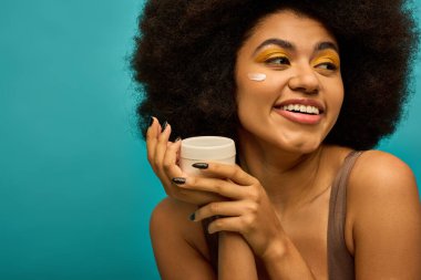 Havalı giyinmiş, gülümseyen ve krem tutan şık Afrikalı Amerikalı kadın..