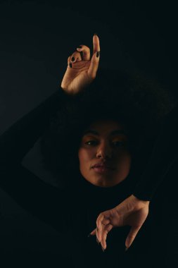 Modaya uygun Afrikalı Amerikalı kadın sevinçle elini renkli arka plana kaldırıyor..