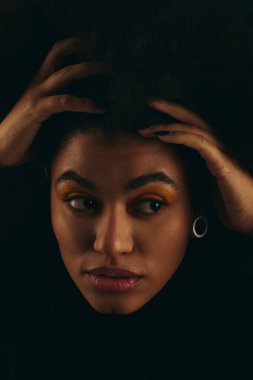 Havalı giyinmiş, elleri başının üstünde, duygularını gösteren Afro-Amerikan bir kadın..