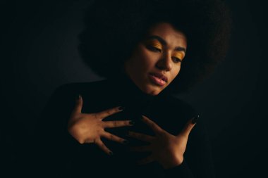 Şık Afro-Amerikan kadın şık giyinmiş, karanlığa uzanıyor..