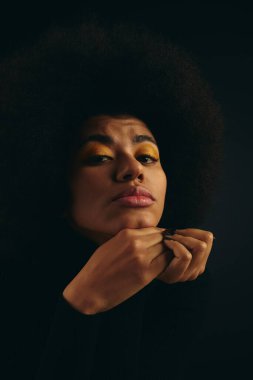 Siyah arka plana karşı parlak sarı göz falı olan şık Afrikalı Amerikalı kadın..