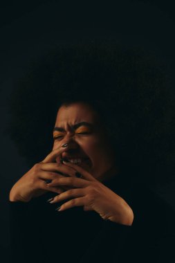 Tarz sahibi Afro-Amerikan kadın moda giyinmiş, elleri yüzü üzerinde..