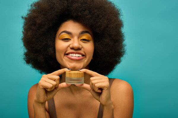 Trendy African American woman with curly hairdohair holding cream.