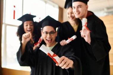 Mezuniyet elbiseleri içinde diploma taşıyan bir grup mutlu öğrenci..
