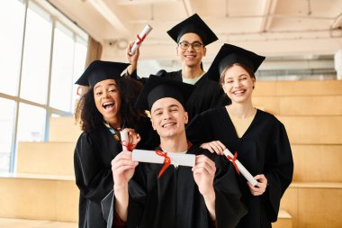 Farklı geçmişlere sahip bir grup öğrenci mezuniyet elbisesi ve kepleri giyip bir kutlama için neşe içinde poz veriyorlar..