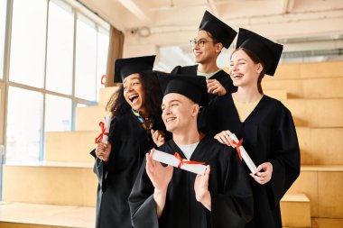 Mezuniyet elbiseleri içinde diploma taşıyan çok kültürlü mutlu mezunlar..