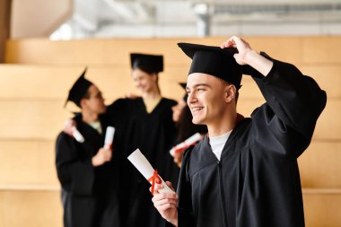 Mezuniyet şapkası ve cübbesi takmış çeşitli bir adam gururla diplomasını elinde tutuyor ve gülümsüyor. Bu da akademik başarıyı gösteriyor..