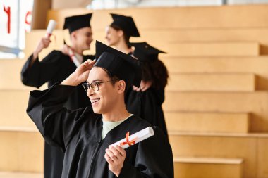 Diploma taşıyan kep ve cüppeli çeşitli bir adam mezuniyetini içeride kutluyor..