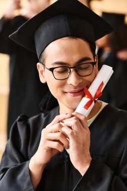 Mezuniyet kepi takmış Asyalı bir adam elinde diplomayla gülümsüyor..