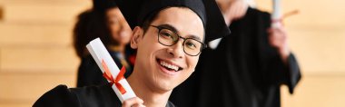 Akademik önlük ve şapkalar içinde çeşitli öğrencilerden oluşan bir grup mezuniyeti kutluyor, diplomaları başarıyla karşılıyorlar..