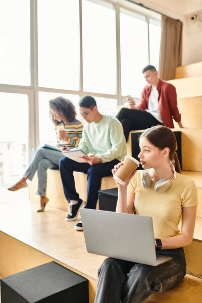 A multicultural woman sits on steps, focused on her laptop with a cup of coffee beside her.