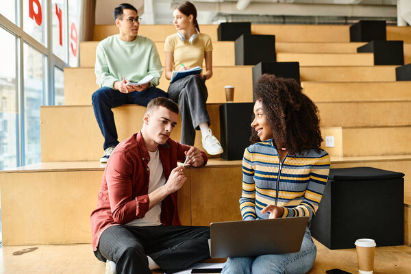 A multicultural group of students sitting around a laptop, engaged in educational activities, brainstorming, and collaboration