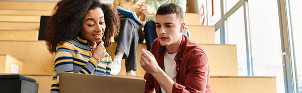 A man and a woman of diverse backgrounds standing at a laptop computer, engaged in academic discussions and research