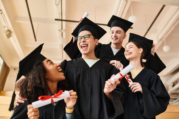 Group of joyful students in graduation caps and gowns celebrating their academic achievements at a university ceremony.