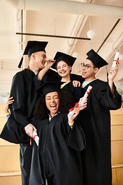 A group of multicultural students in graduation gowns, celebrating their academic success while posing for a picture.