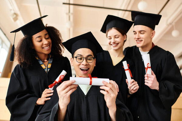A diverse group of graduates in graduation gowns holding diplomas, celebrating their academic achievement together.