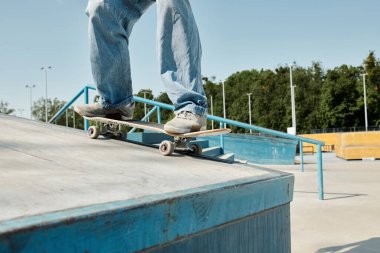 A young skater boy fearlessly rides his skateboard down the side of a ramp at a skate park on a sunny summer day. clipart