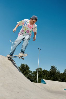 A young skater boy rides a skateboard down the ramp at an outdoor skate park on a sunny summer day. clipart