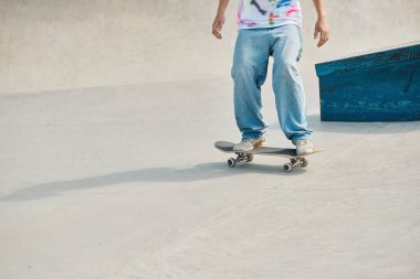 A young skater boy riding a skateboard down a cement ramp in a vibrant outdoor skate park on a sunny summer day. clipart