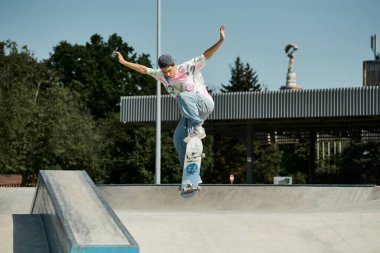 A young skater boy fearlessly riding a skateboard up the steep side of a ramp at an outdoor skate park on a sunny summer day. clipart