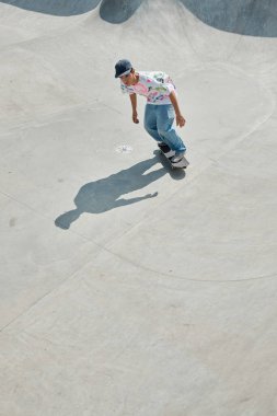A young man rides his skateboard down a ramp in a skate park on a sunny summer day. clipart