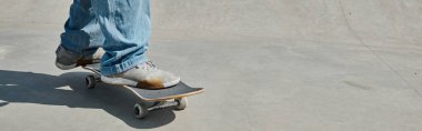 A young skater boy showcases his skills as he rides a skateboard on a cement surface in a vibrant urban skate park on a sunny day. clipart