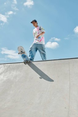 Young skater boy confidently riding skateboard up the side of a steep ramp in a sunny outdoor skate park. clipart