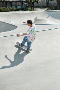 A young man skillfully rides a skateboard upwards on the side of a ramp in a vibrant outdoor skate park on a sunny day. clipart