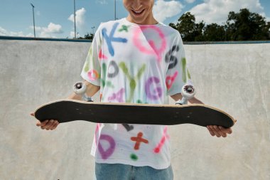 A young man with a skateboard in a vibrant skate park, capturing the essence of freedom and adrenaline while skating outdoors in the summer. clipart