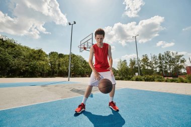 Sahada durup basketbol oynamaya hazırlanan genç bir adam..