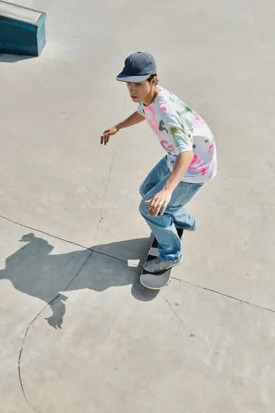 stock image A young man effortlessly rides a skateboard down a cement ramp in a vibrant skate park on a sunny summer day.