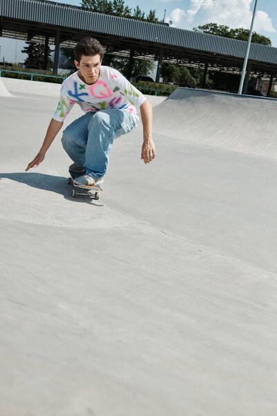 A young skater boy rides his skateboard down the side of a ramp in a sunny outdoor skate park on a summer day.
