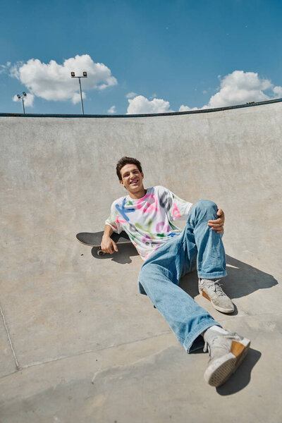 Молодой скейтбордист изящно сидит на скейтборде, умело маневрируя через скейтпарк в солнечный летний день..