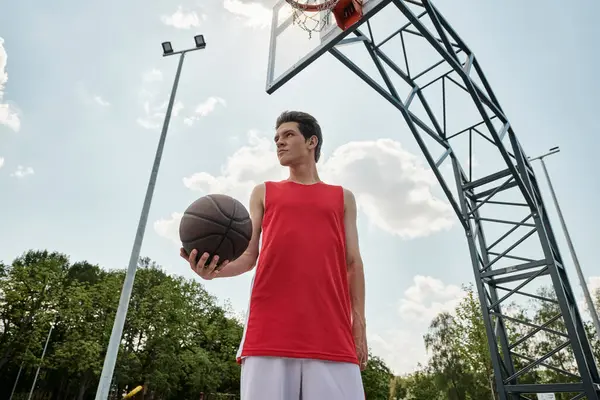 Ung Man Röd Skjorta Står Utomhus Och Håller Basketboll Handen — Stockfoto