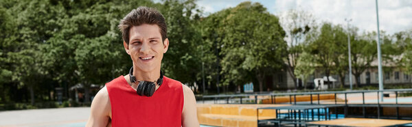 Молодой человек в красной рубашке погружен в музыку, в наушниках, потерявшись в ритме.