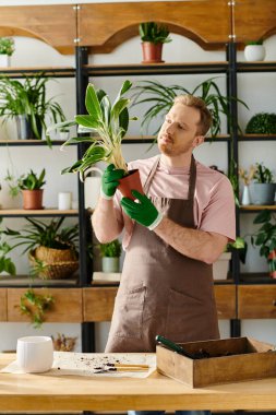A skilled man in an apron delicately holds a potted plant in a cozy plant shop, embodying the essence of nurturing and growth. clipart