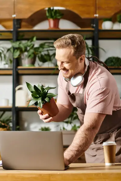 Man Sporting Headphones Concentrates His Laptop Immersed Managing His Plant — Stok Foto