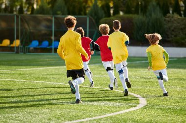 A vibrant scene unfolds as a group of young boys play a game of soccer on a grassy field, kicking the ball with enthusiasm and chasing after it. Their energy and camaraderie create an exciting and dynamic moment. clipart