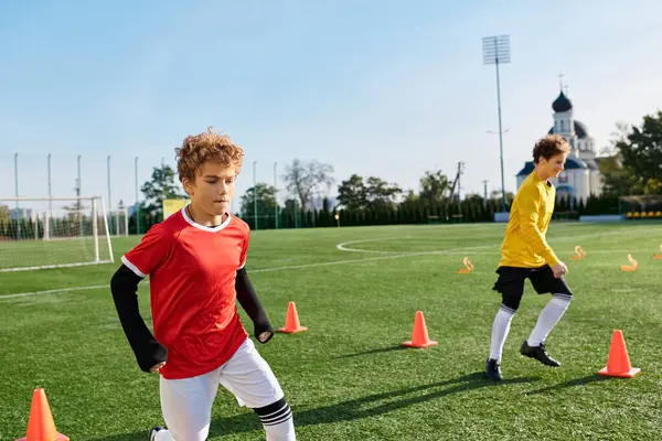 İki genç adam çimenli bir alanda tutkuyla futbol oynuyorlar. Top sürüyorlar, pas veriyorlar ve atıyorlar. Oyun oyunlarında yetenek ve takım çalışması sergiliyorlar..