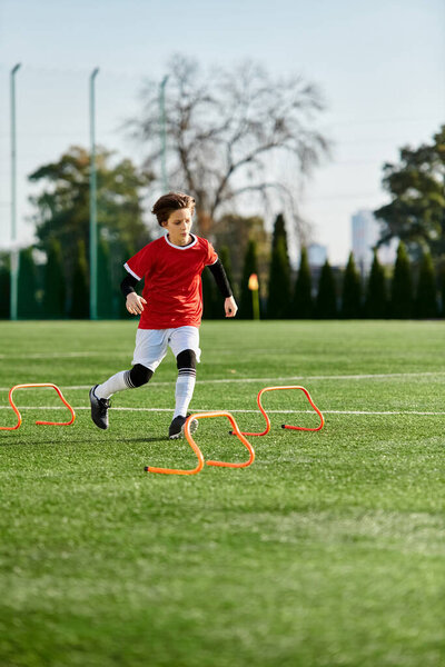 A young boy is skillfully kicking a soccer ball across a vast field, displaying agility and precision in his movements.
