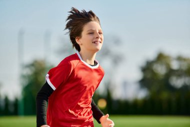 A dynamic scene on a soccer field, showcasing a young boy running with determination. His energy and passion for the game are evident as he sprints across the lush green field, embodying the spirit of sportsmanship and athleticism. clipart