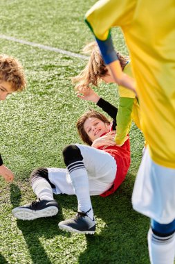 Çimenli bir alanda tutkulu bir şekilde futbol oynayan, topa vuran, koşan ve birbirlerine tezahürat yapan bir grup genç..