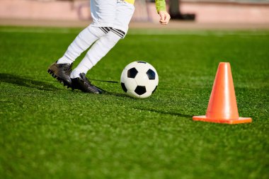 Bir külahta topu tekmelerken etkileyici futbol becerileri sergileyen genç bir çocuk sahada çevikliğini ve hassasiyetini gösteriyor..